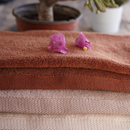 3 Bath towels with flower petals overtop a wooden table