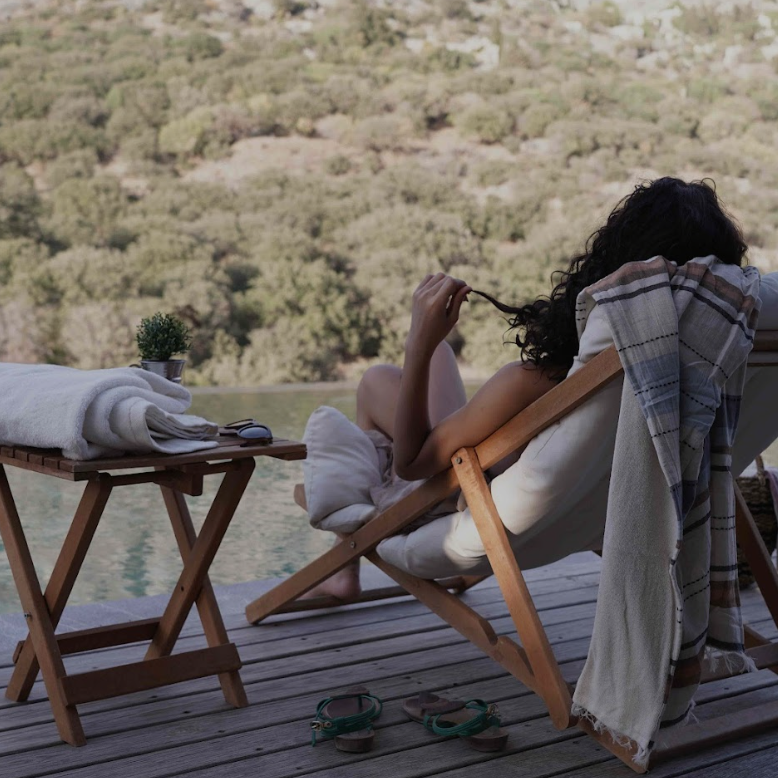 Luxurious Turkish beach towels draped over wooden loungers beside a serene pool, showcasing Minoa Home’s sustainable summer essentials for coastal, resort, or poolside living.