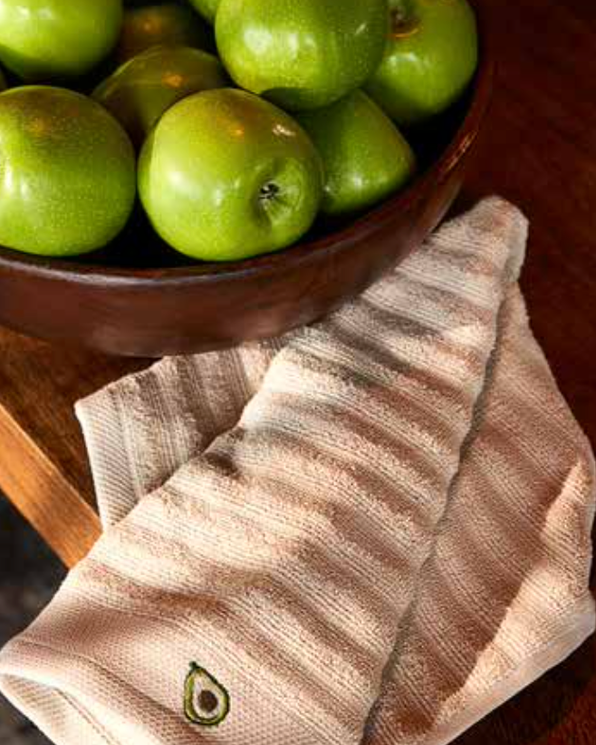 Kitchen Towel - Vera in beige, placed on a kitchen table with fresh apples beside it, showcasing its soft cotton fabric and absorbent quality