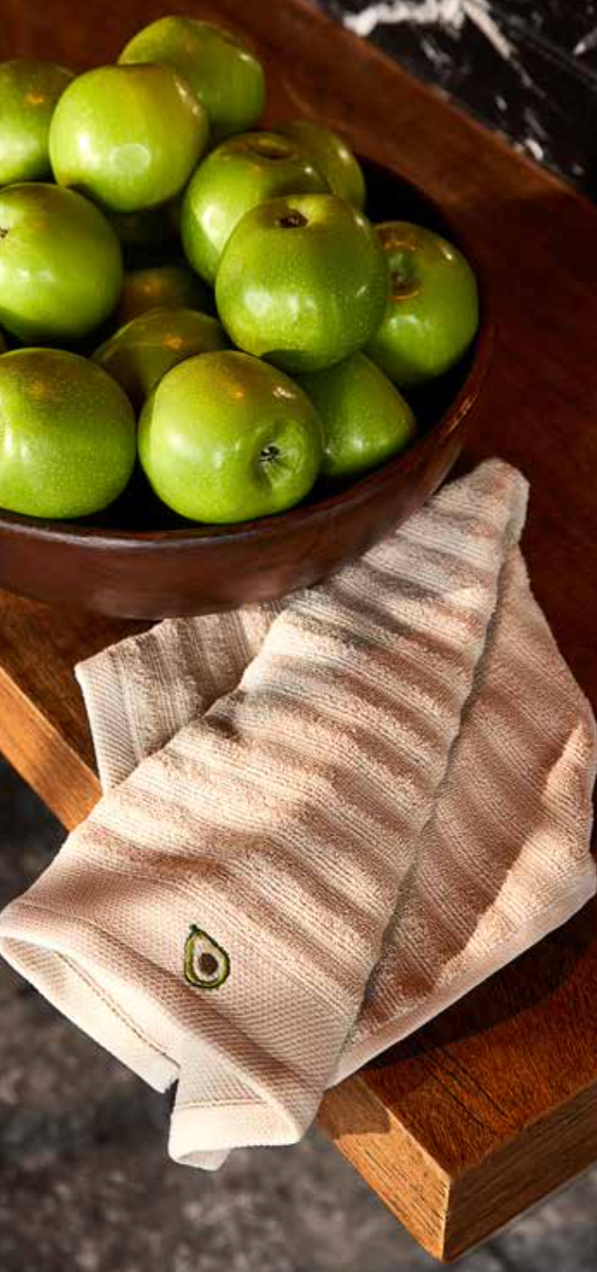 Kitchen Towel - Vera in beige, placed on a kitchen table with fresh apples beside it, showcasing its soft cotton fabric and absorbent quality