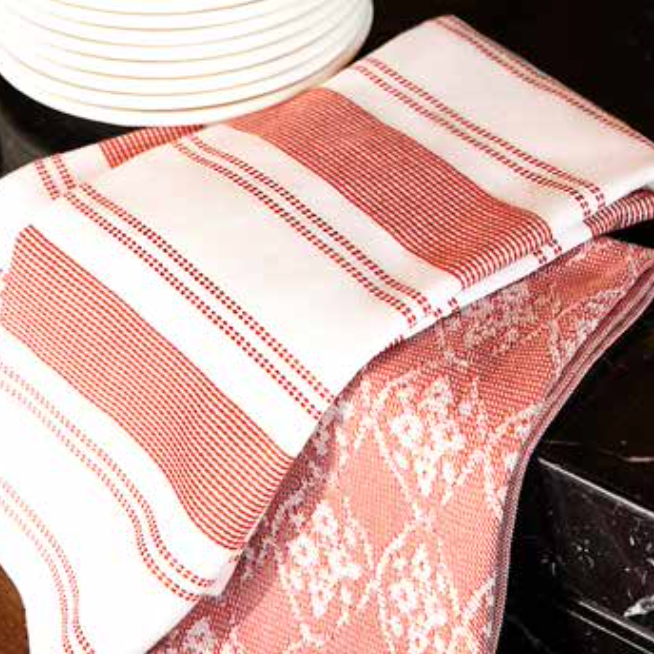 Kitchen Towel - Viva in red, placed on the kitchen table, featuring a soft, absorbent cotton design for practical use and a pop of colour