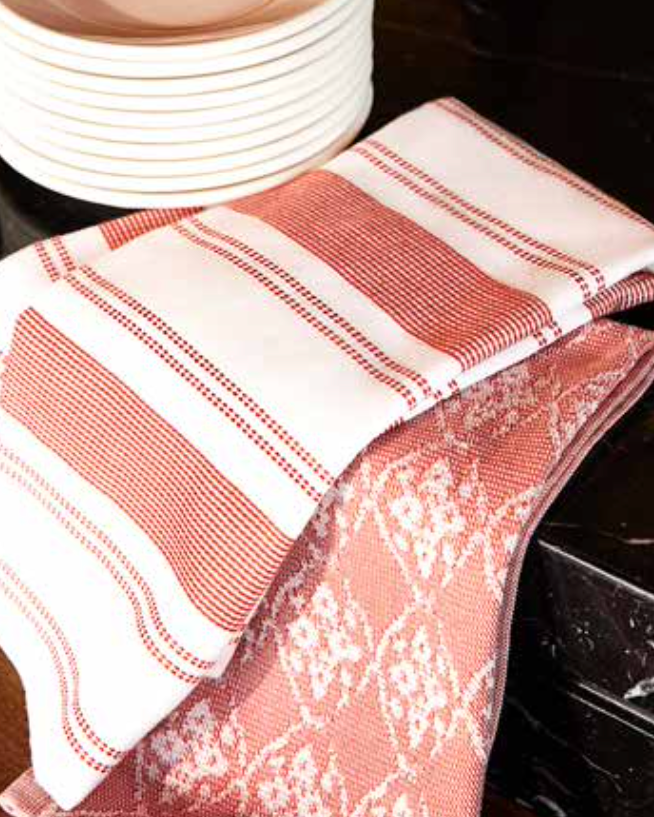 Kitchen Towel - Viva in red, placed on the kitchen table, featuring a soft, absorbent cotton design for practical use and a pop of colour