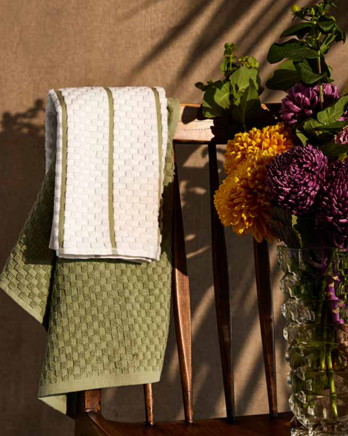 Kitchen Towel - Mika set in green, draped over a chair, showcasing its soft cotton fabric and absorbent design, perfect for everyday kitchen use