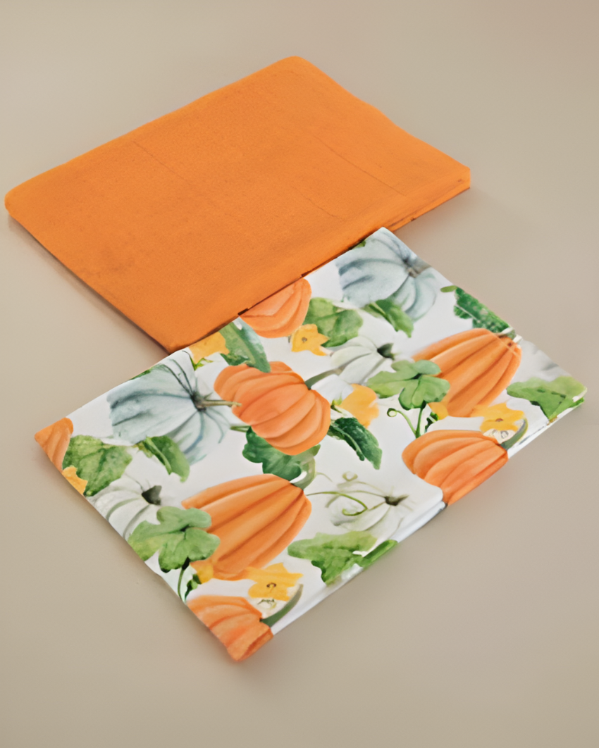 Two kitchen towels, one orange and one with pumpkin pattern, on a beige surface.