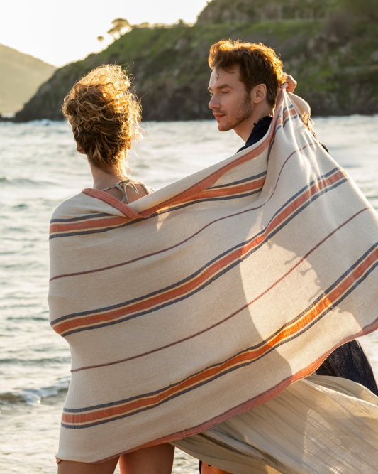 Beautiful, luxury Elba Turkish Towel crafted with organic material wrapped around two people under the sunshine