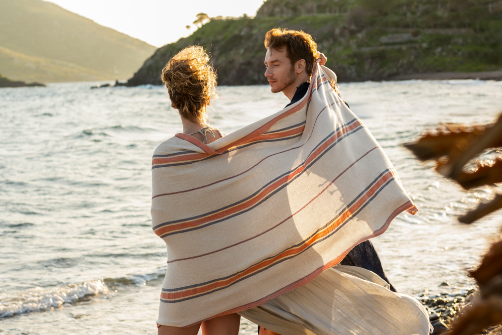 Beautiful, luxury Elba Turkish Towel crafted with organic material wrapped around two people under the sunshine