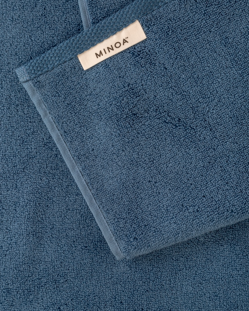 Blue towel with Minoa label on a matching background