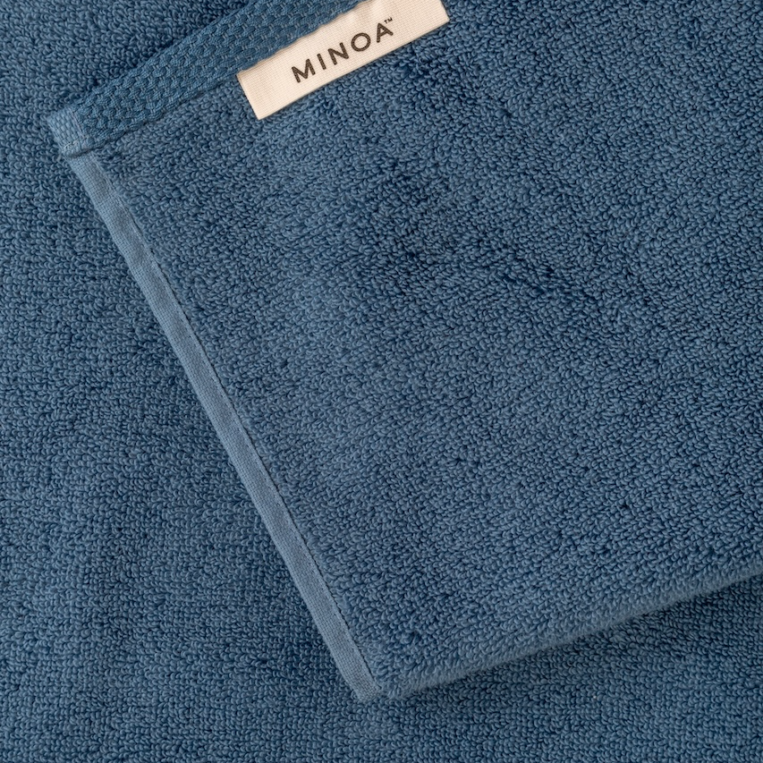Blue towel with Minoa label on a matching background