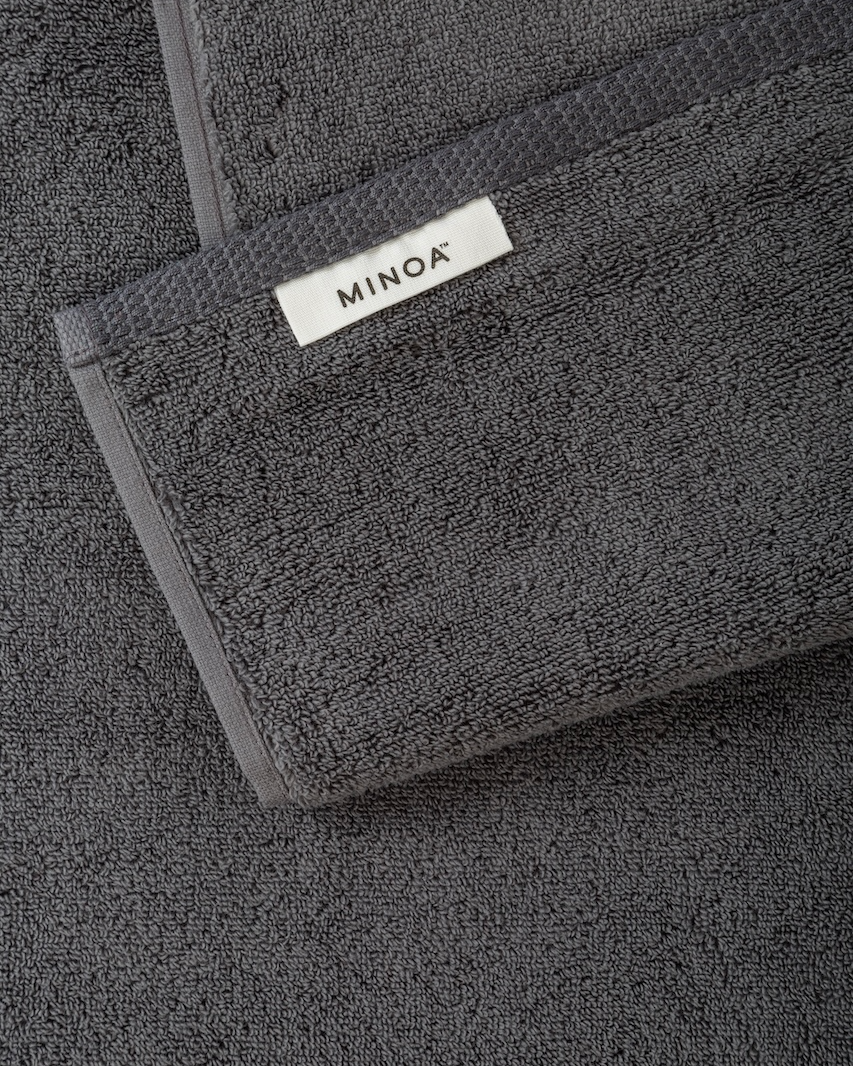 Dark gray towel with Minoa logo on a matching background