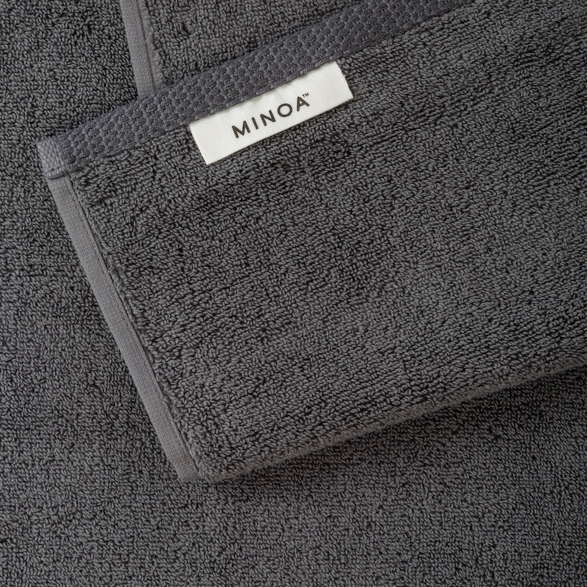 Dark gray towel with Minoa logo on a matching background