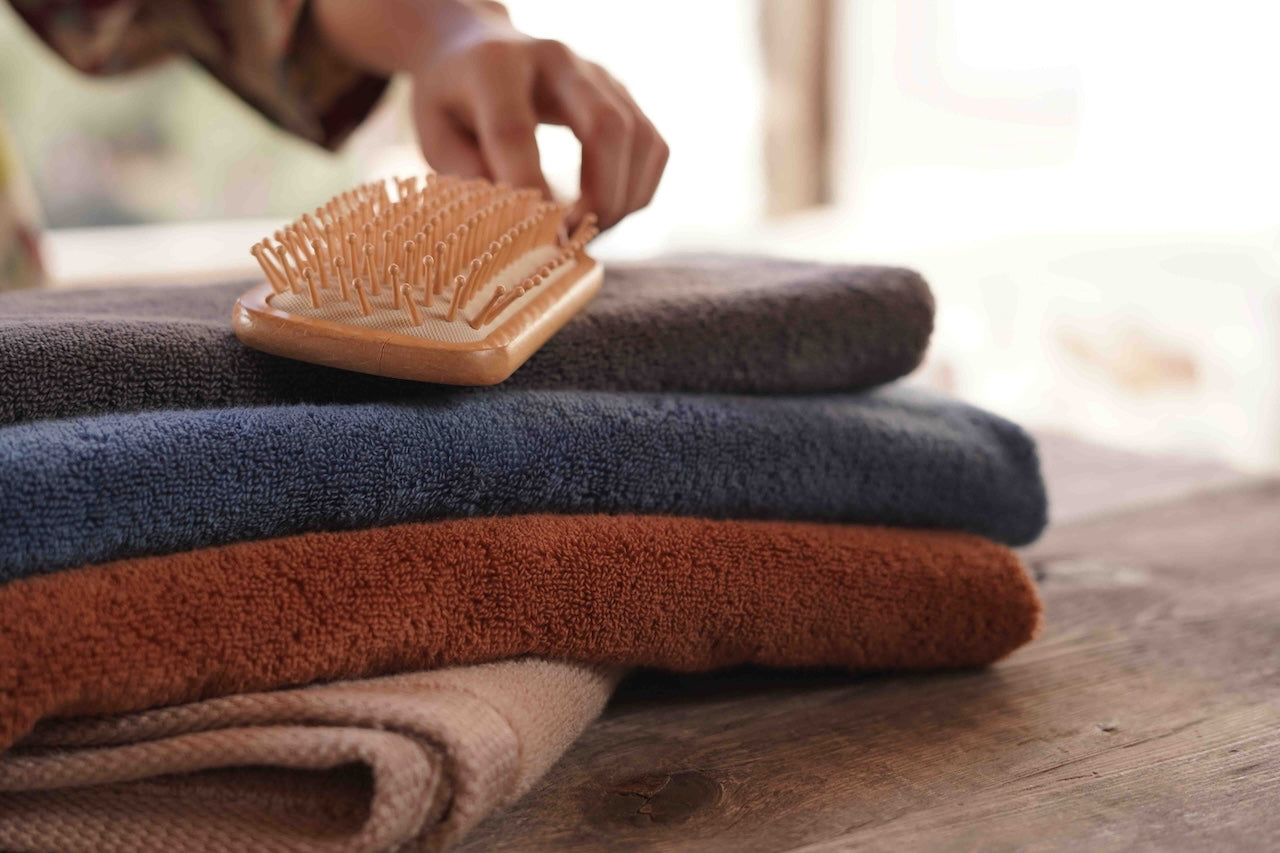 Minoa USA Canada sustainable luxury bath towels Plush Lite Aegean Cotton bath towel pack of four with a brush on top, highlighting soft texture, premium quality, and elegant design