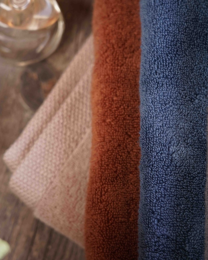 Minoa USA Canada organic bath towels Plush Lite Aegean Cotton medium bath and guest hand towel set pack of two on a wooden surface with nail polish beside, highlighting soft texture and premium quality