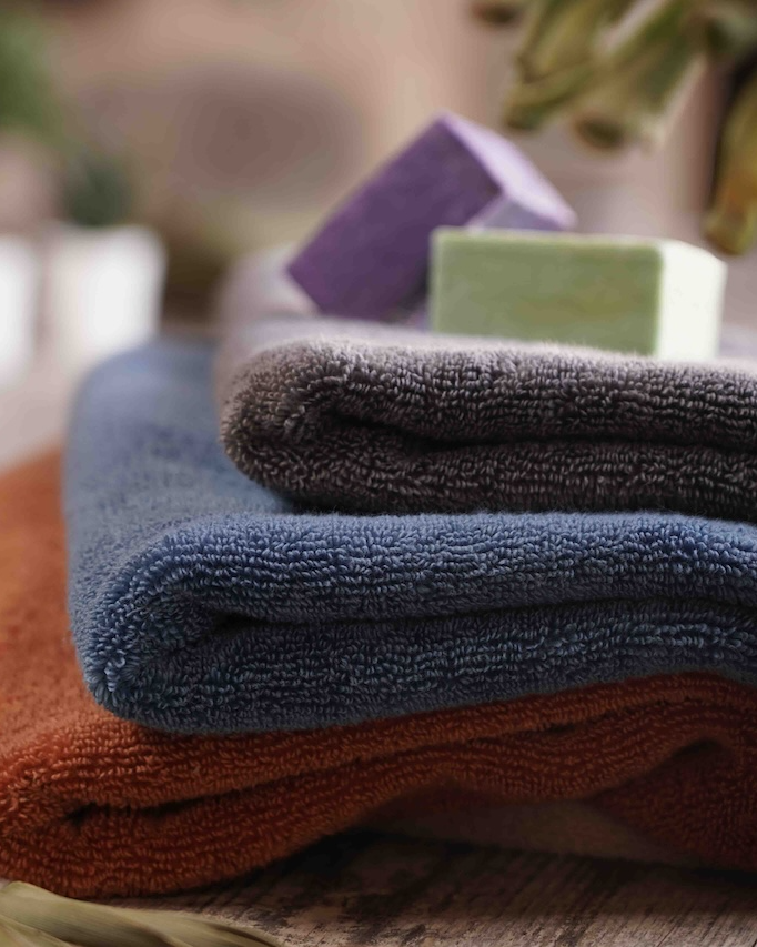 Minoa Plush Lite Aegean Cotton large bath and hand towel set styled with soaps showcasing sustainable luxury and the soft absorbent quality of organic bath towels and luxury bath towels