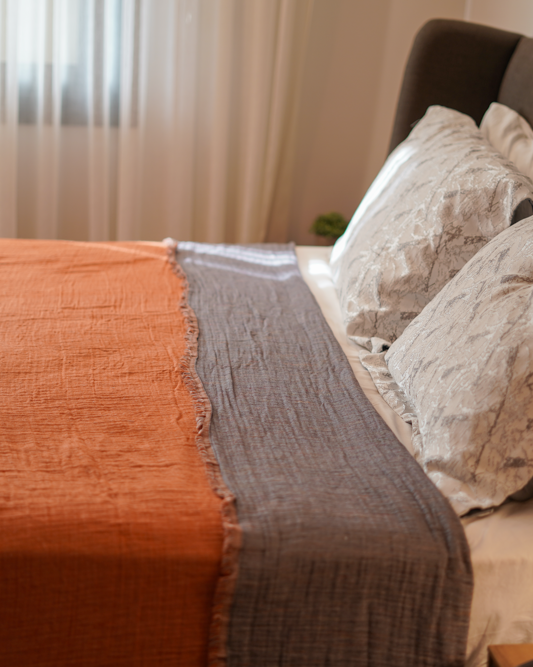 Reversible Muna organic gauze bed spread in Terra, draped on bed, soft texture, warm earthy hue, elegant design with organic cotton sheets.
