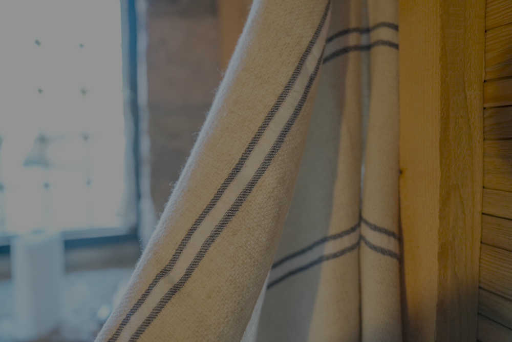 Blue and white Anakao 215 gram Aegean Cotton and Linen Turkish towel hanging on the wall showcasing the soft texture of an organic bath towel