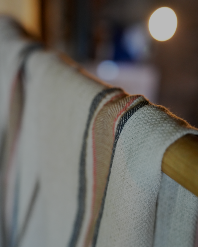 Luxury and organic Sand & Navy Elba Turkish Towel hanging on a cloth hanger in a room