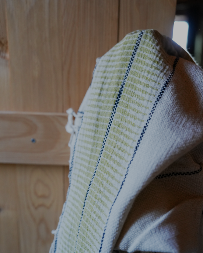 Luxuriously soft and sustainable Palawan 220-gram organic linen Turkish bath towel in green hanging on a doorknob, highlighting plush texture and eco-friendly design