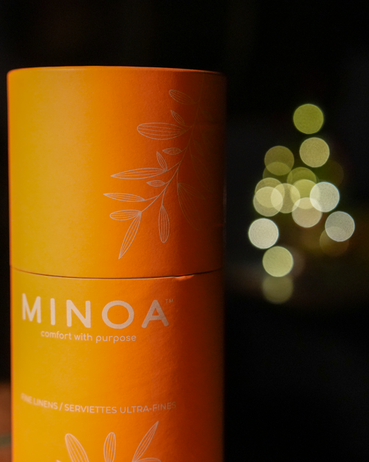 Close-up of Plush Lite 500-Gram Aegean Cotton luxury bath towels guest bath and hand towel set in a luxurious orange cylinder case with dark navy green case in the background