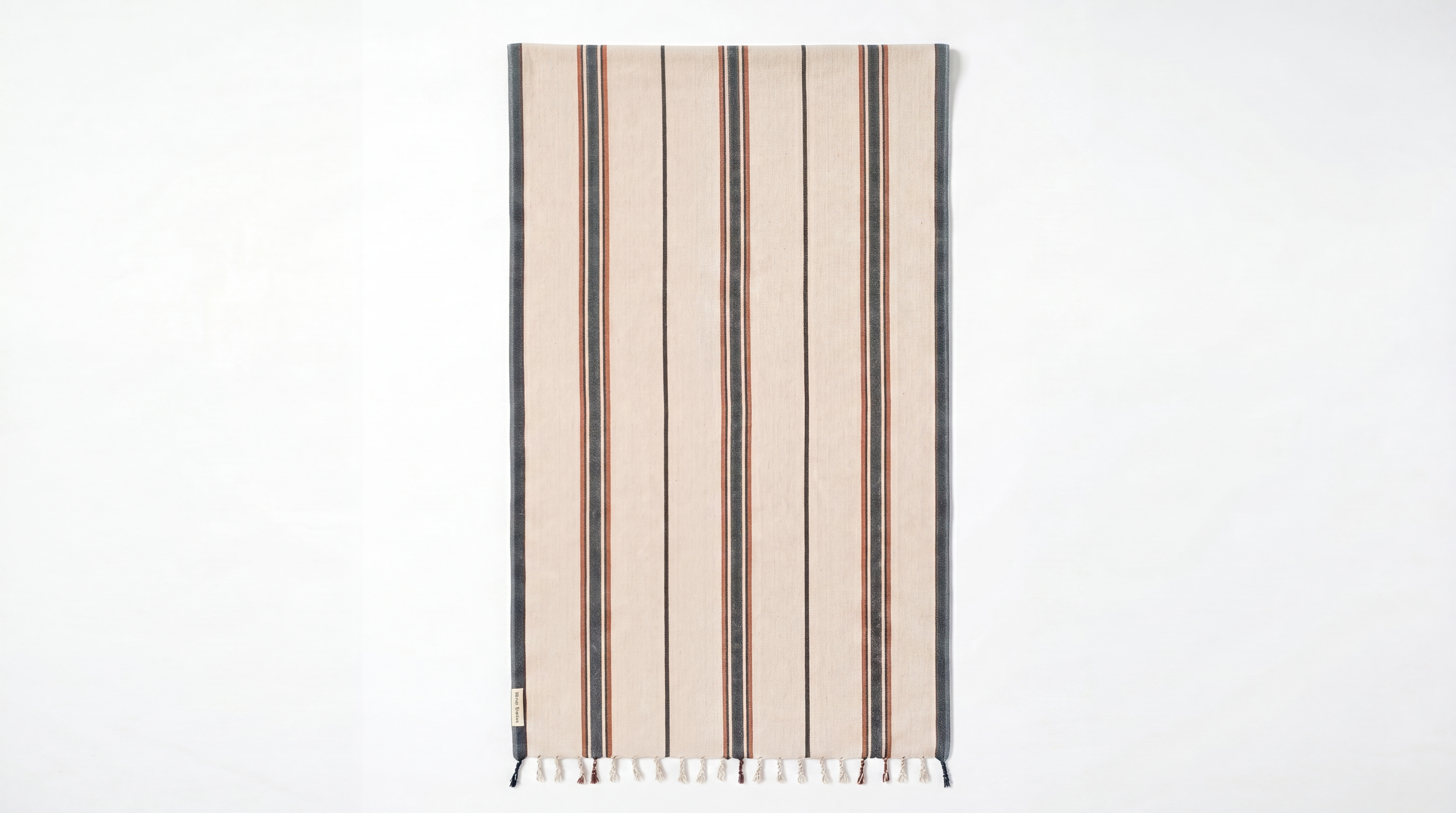 A rectangular woven towel with vertical stripes in beige, brown, and dark gray, finished with fringe along the bottom edge, shown against a plain white background.