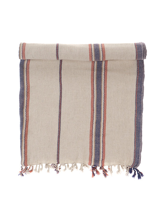 Folded navy & red towel with striped pattern and tassels on a white background