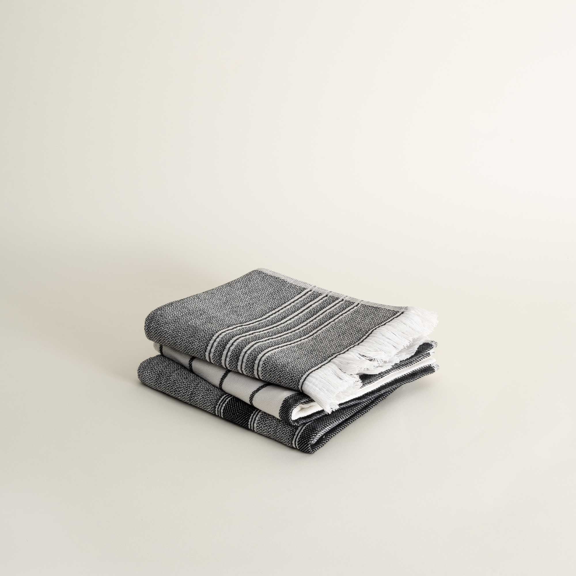 Stack of dark grey folded towels on a light beige background