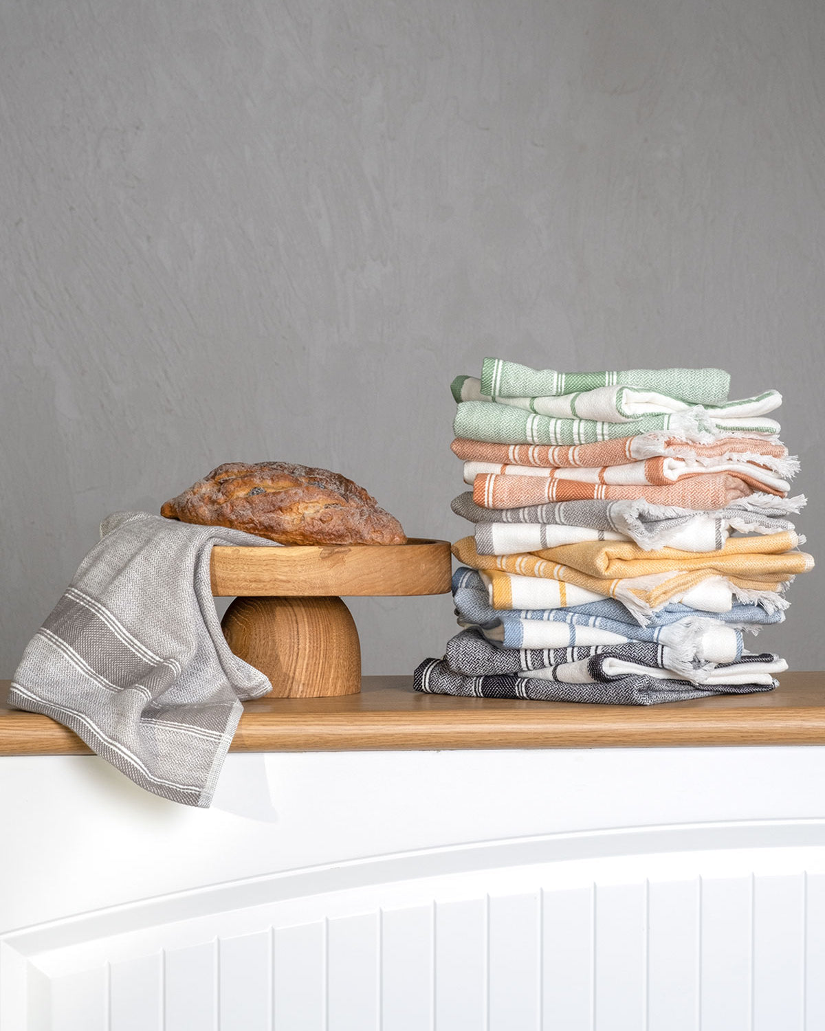 Elis Organic Aegean Cotton Kitchen Towel set of 3, featuring Lime Breeze, Silver Symphony, Midnight Velvet, Spice Serenade, Lemon Zest, and Serene Sky, neatly folded beside a loaf of bread