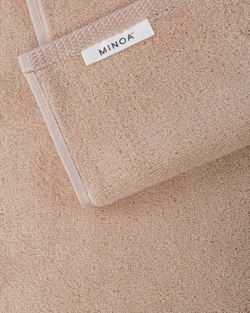 Close-up of a beige towel with a visible brand label on a matching background.