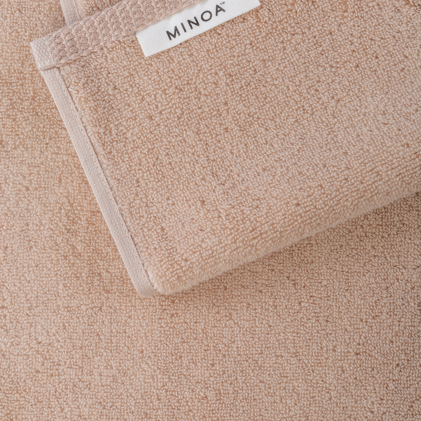 Close-up of a beige towel with a visible brand label on a matching background.