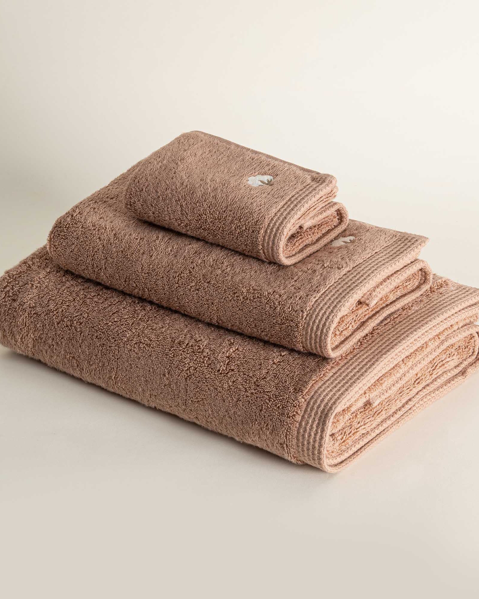 Side view of folded Jasper 600-gram organic Aegean cotton luxury bath, hand, and washcloth towels in Amber Amour, showcasing soft plush texture, rich tone, and luxurious fabric