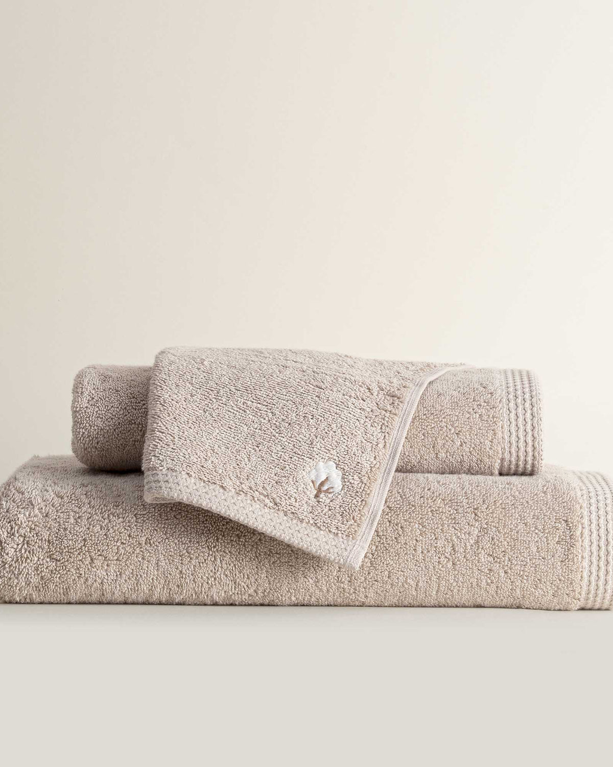 Three folded Jasper 600-gram organic Aegean cotton luxury bath, hand, and washcloth towels in Vanilla Embrace, showcasing soft plush texture, warm color, and luxurious fabric