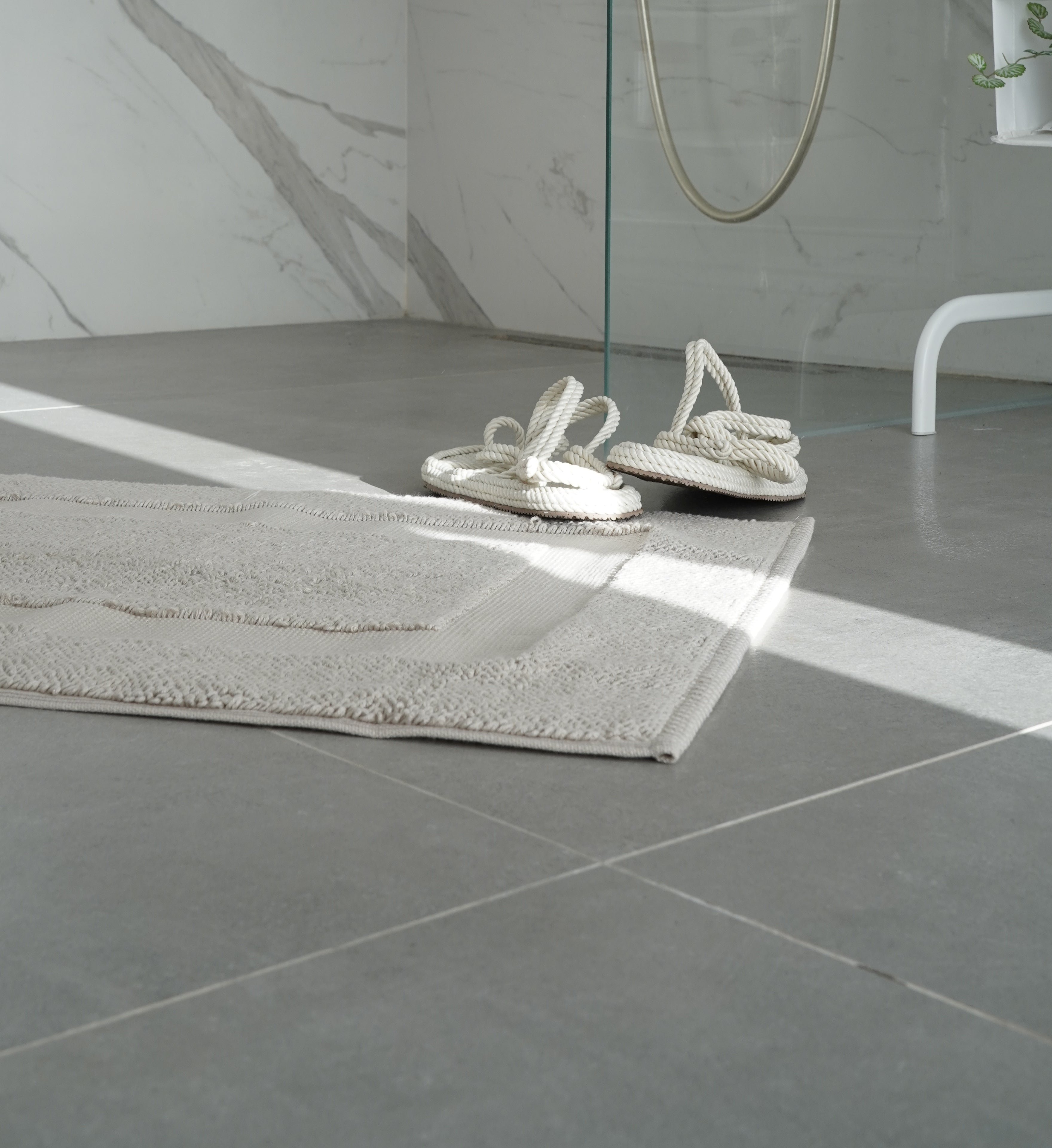 Kaia Aegean Cotton Bath Mat in Pearl Petal colour, placed in a shower room setting, showcasing its soft texture, elegant colour, and luxurious fabric