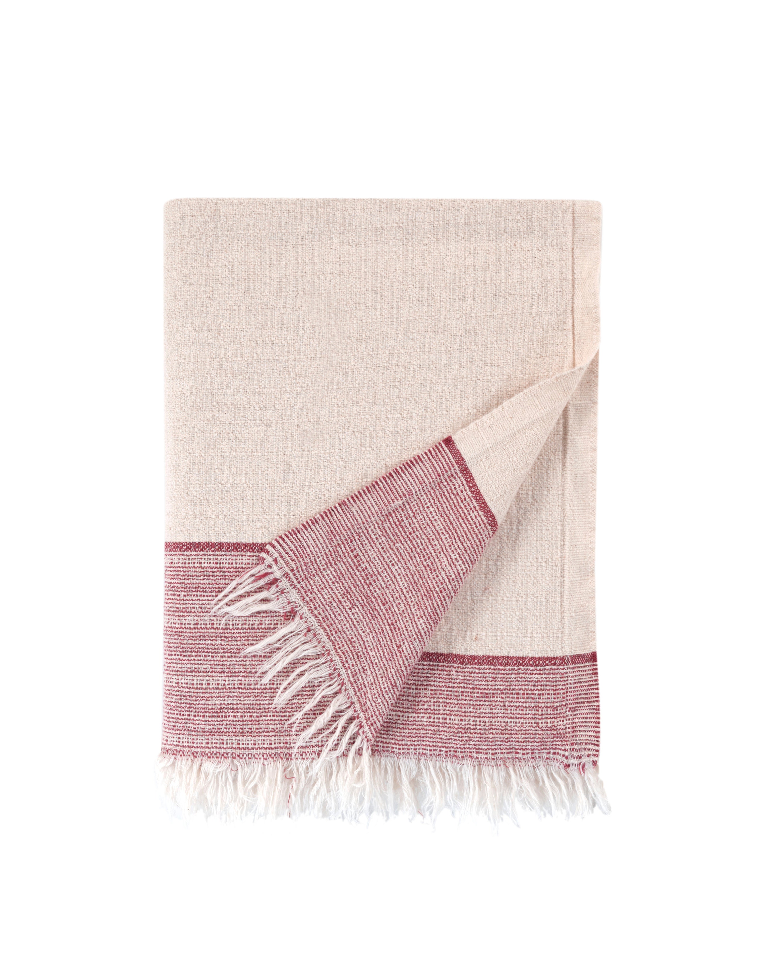 Beige and pink woven towel with fringes on a white background