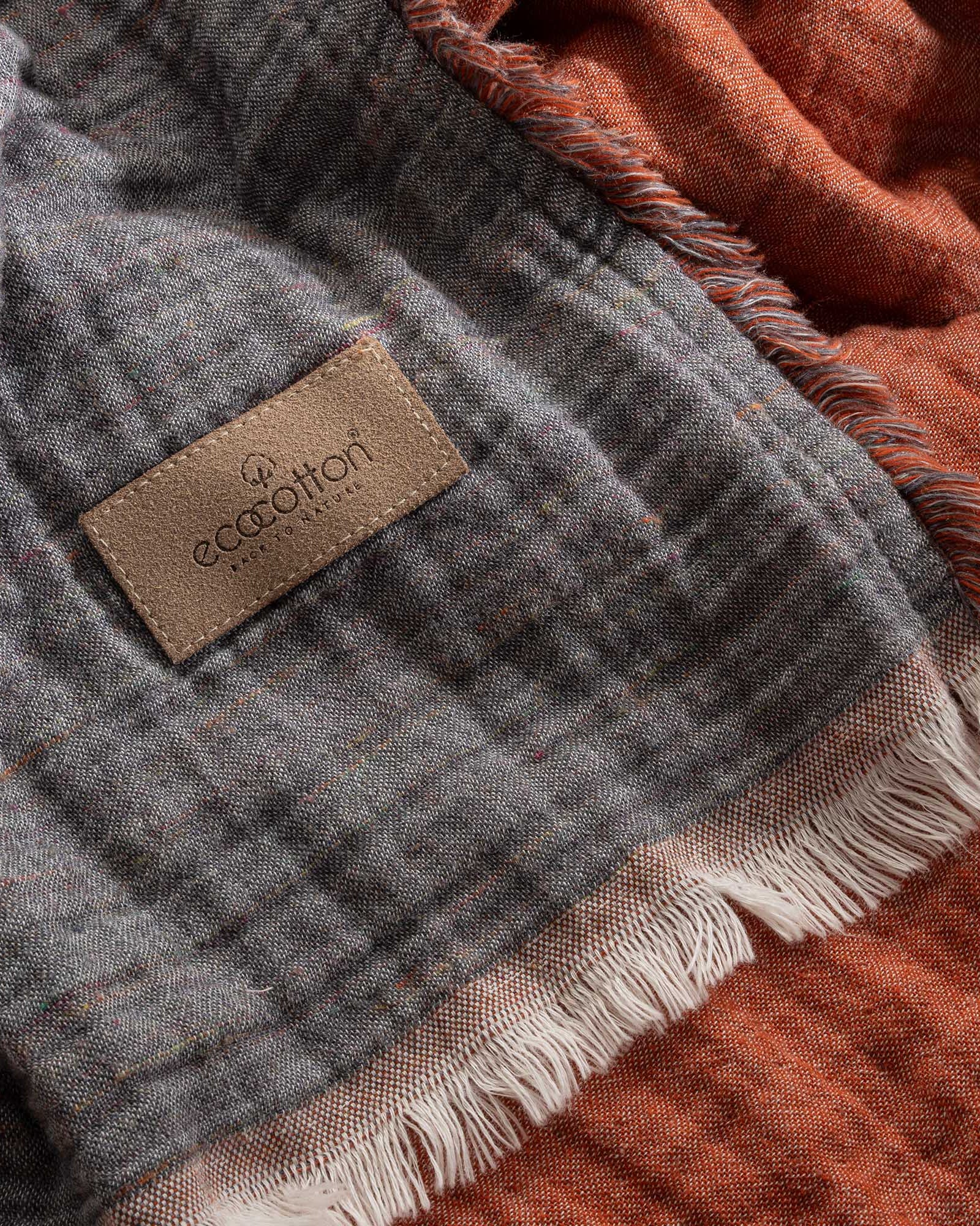 Close-up of reversible Muna organic gauze bed spread in Terra, soft texture, earthy tone, Ecocotton tag with organic cotton sheets.