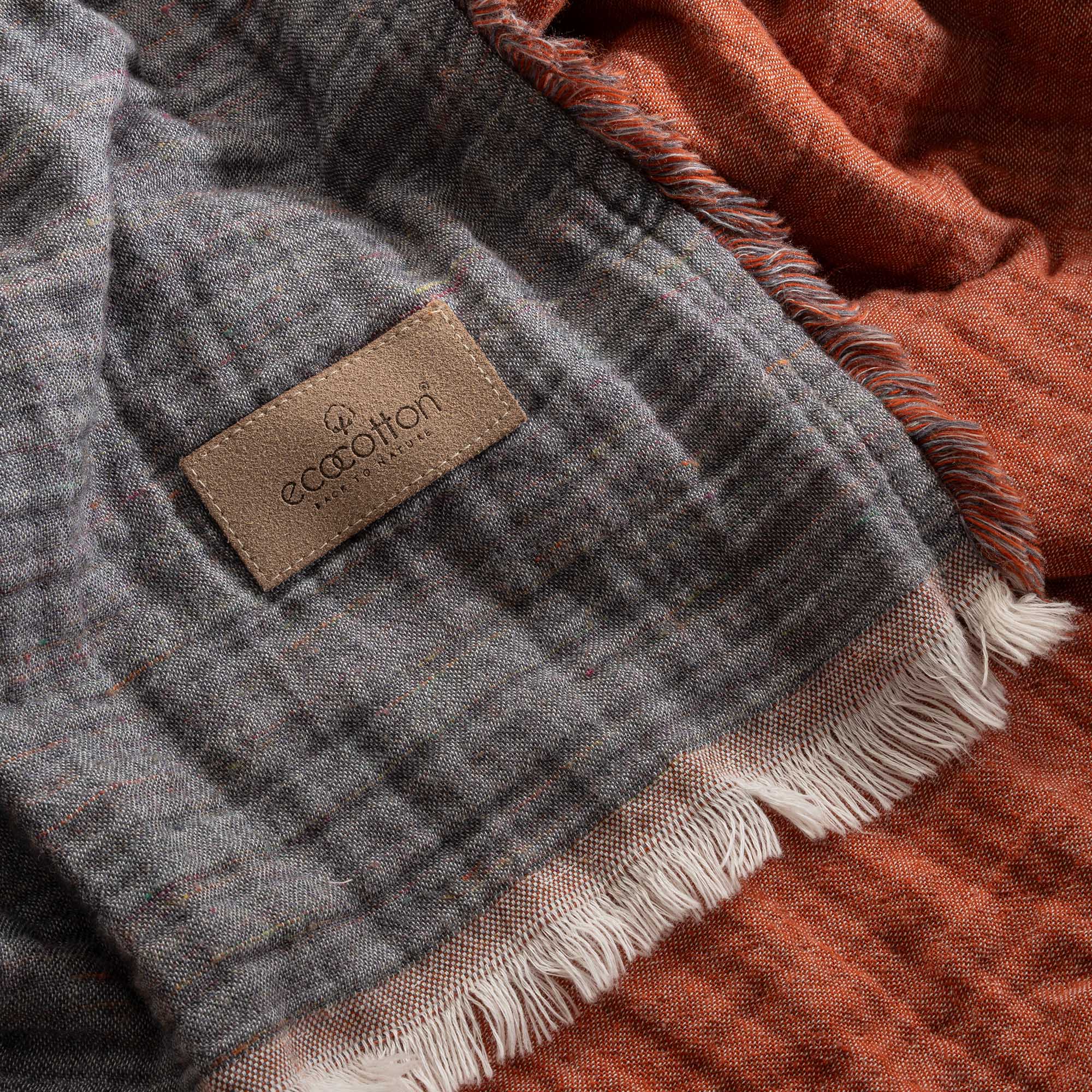 Close-up of reversible Muna organic gauze bed spread in Terra, soft texture, earthy tone, Ecocotton tag with organic cotton sheets.