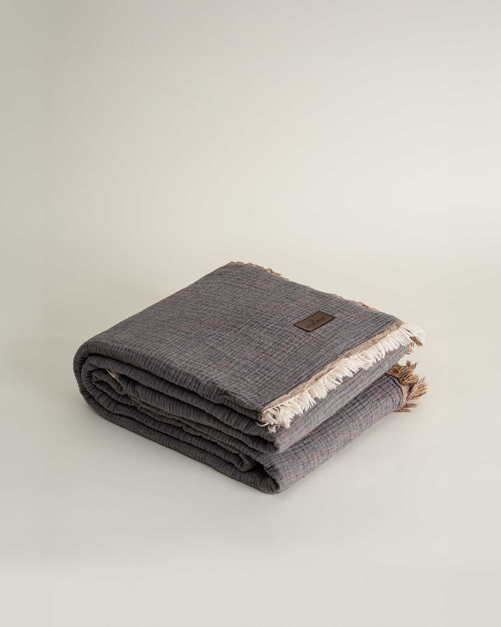 Neatly folded reversible Muna organic gauze bedspread in Mustard, soft texture, vibrant hue, designed to pair with organic cotton sheets.