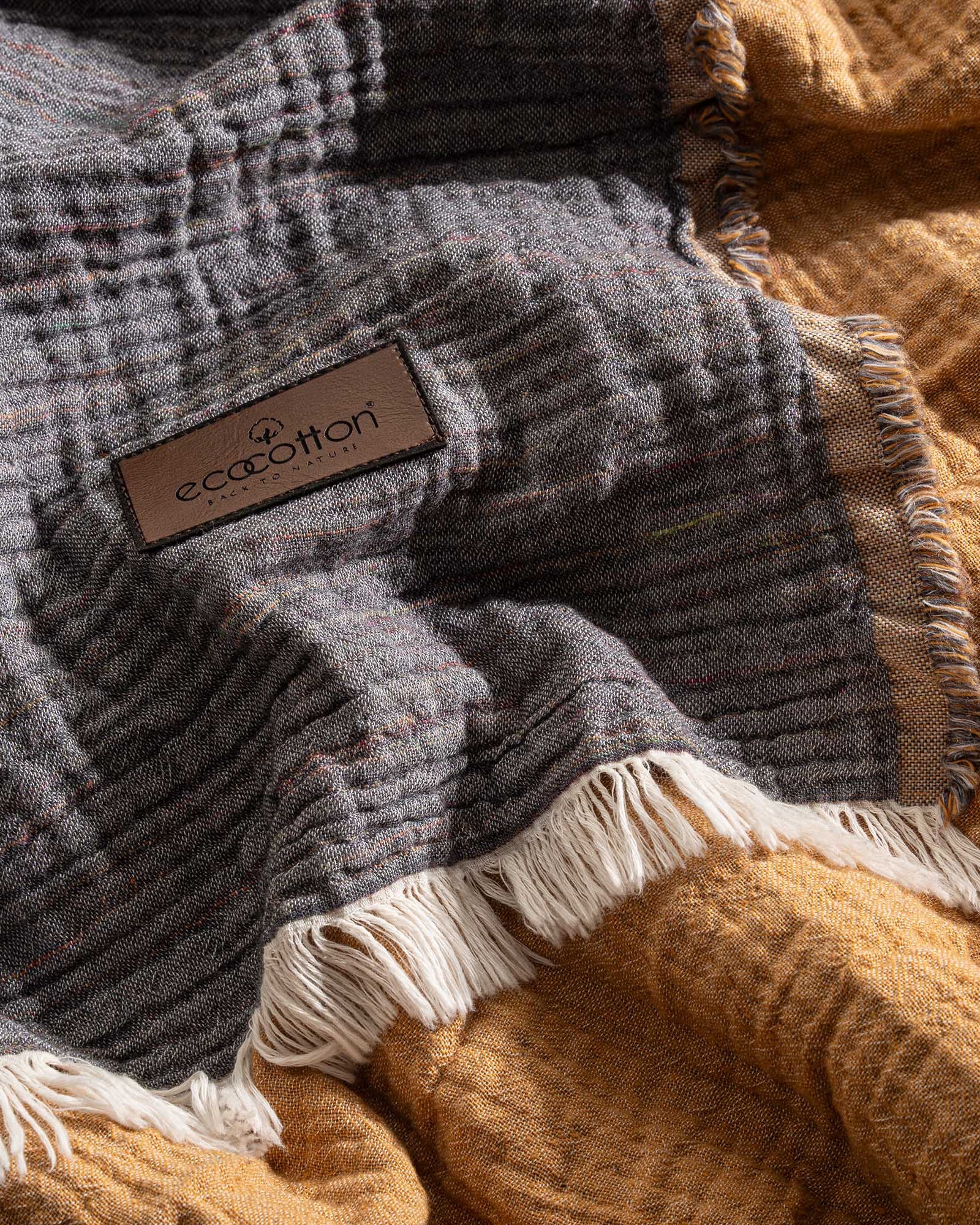 Close-up of the Reversible Muna organic gauze bedspread in Mustard, soft texture, rich color, fine craftsmanship with organic cotton sheets.