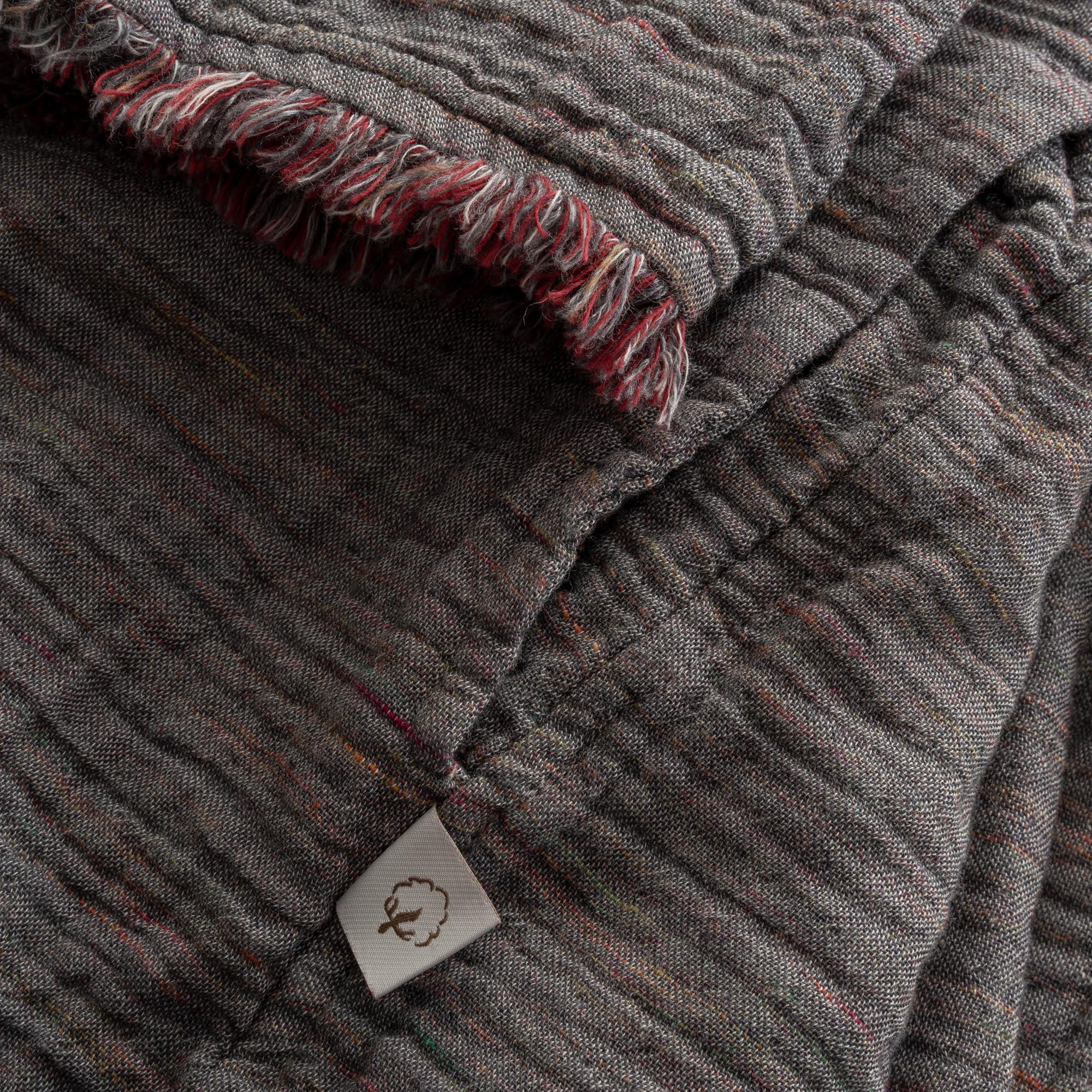 Close-up of the sleeve of the Women's Muna Organic Aegean Cotton Gauze Two-Sided Robe in Bordeaux Bliss, showcasing the fabric's detailed stitching and elegant design