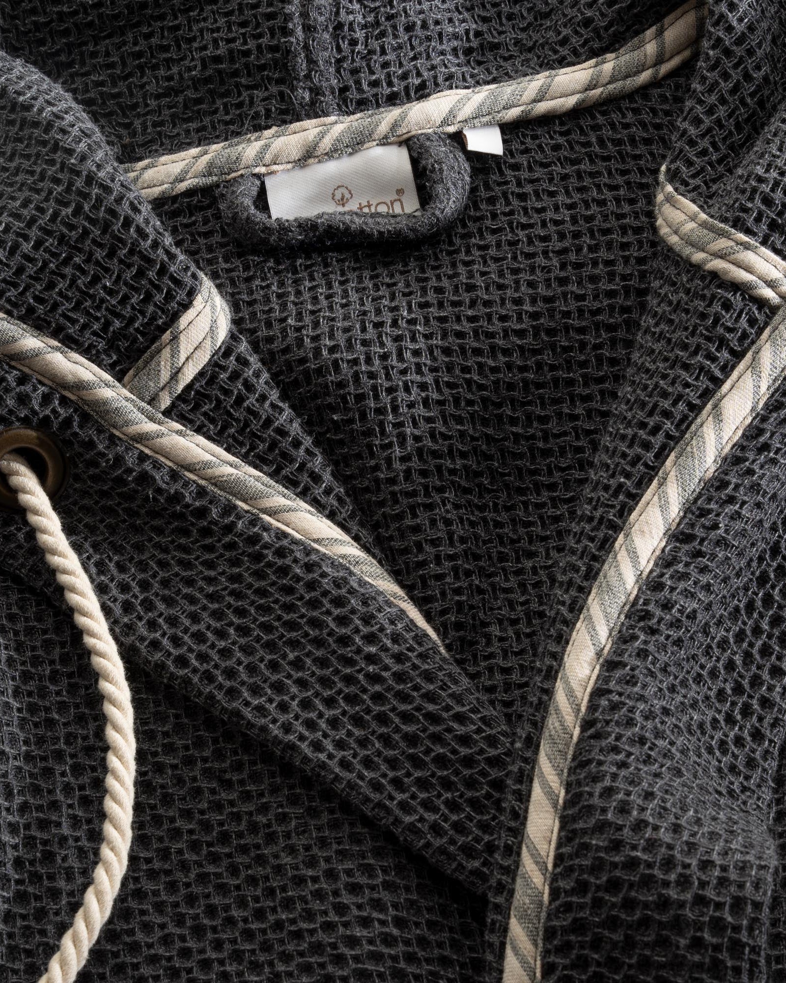 A close up shot of Minoa's Naia Panama Weave Mens Robe showing the EcoCotton Brand Tag