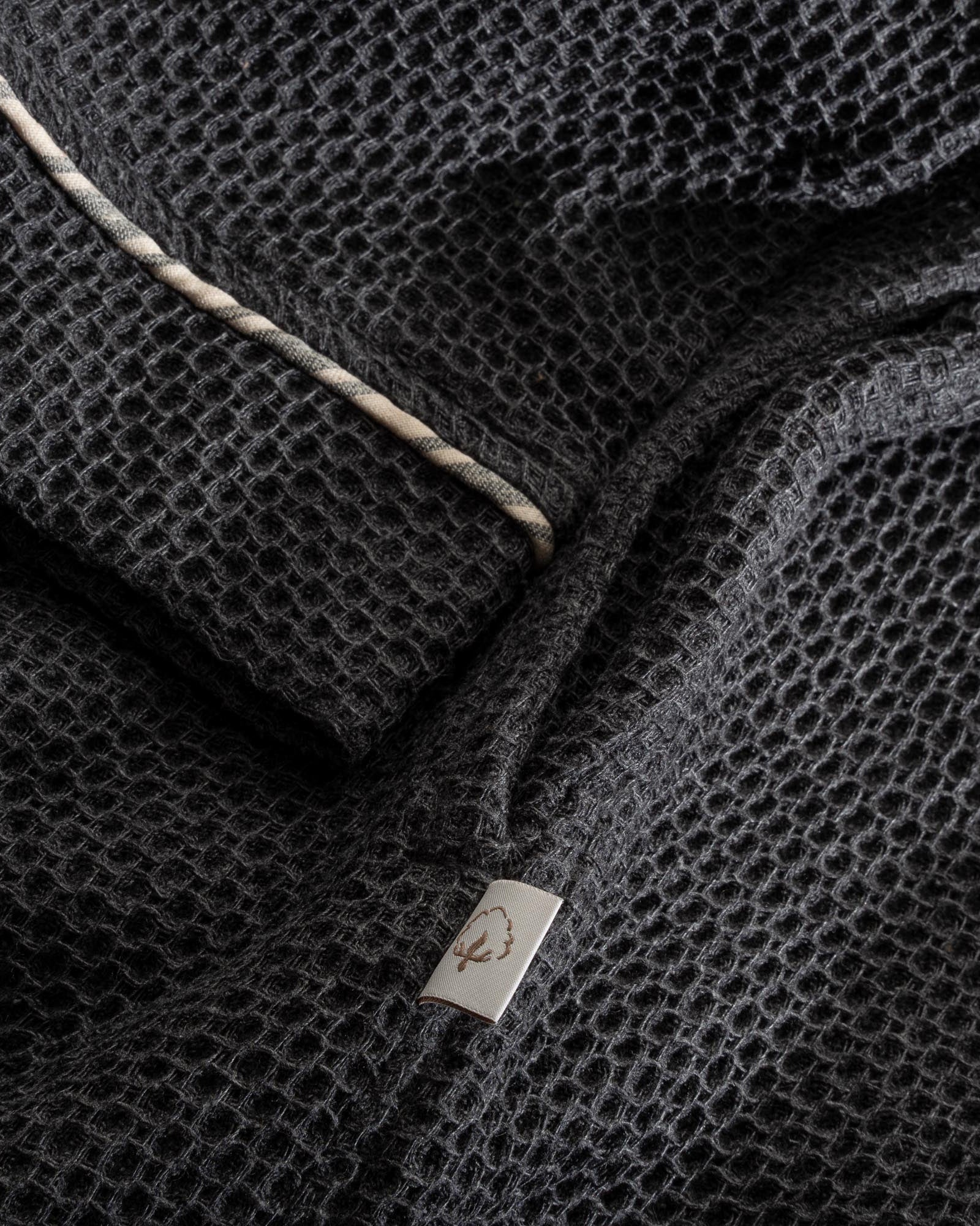 A close up shot of Minoa's Naia Panama Weave Mens Robe showing its robe sleeve with delicate texture