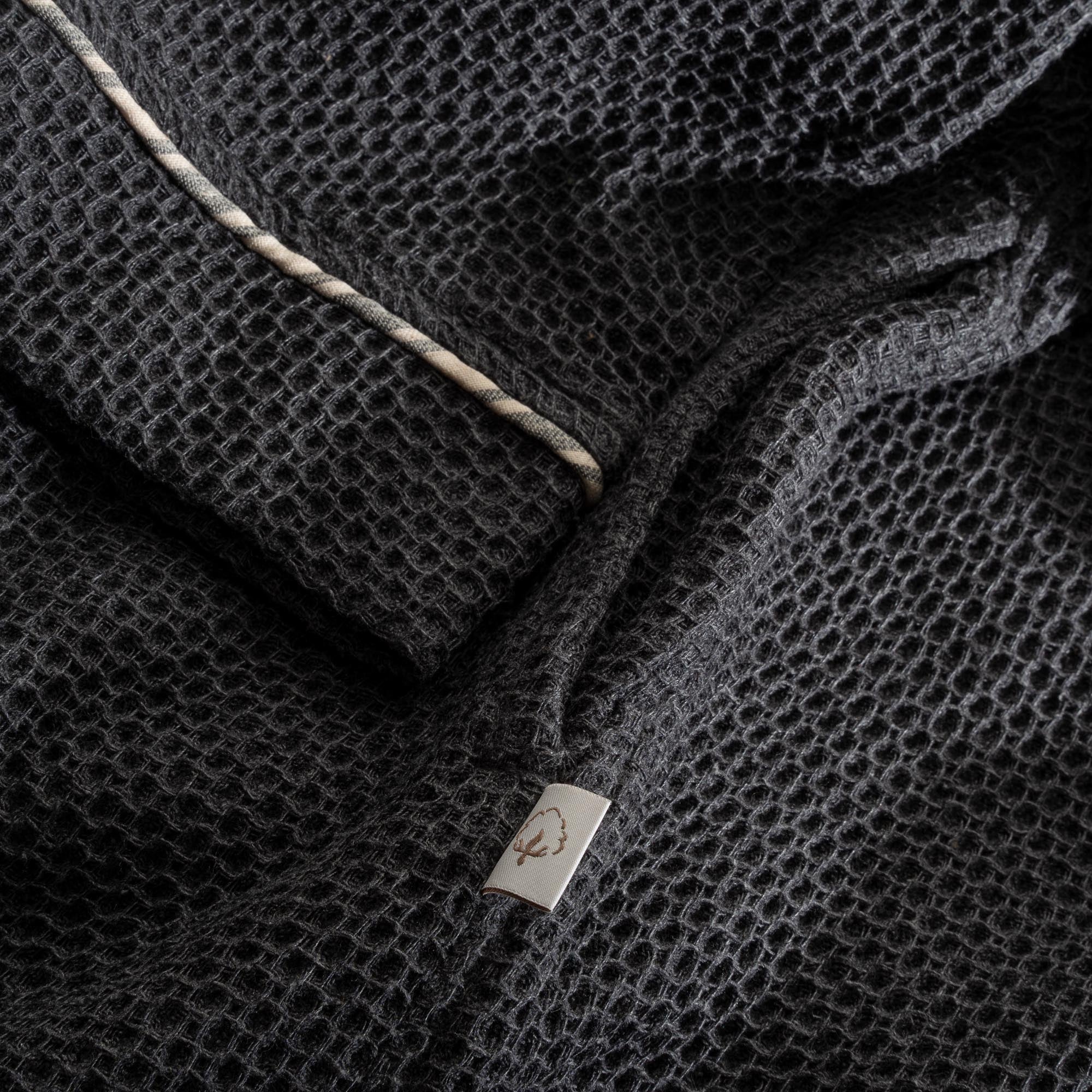 A close up shot of Minoa's Naia Panama Weave Mens Robe showing its robe sleeve with delicate texture