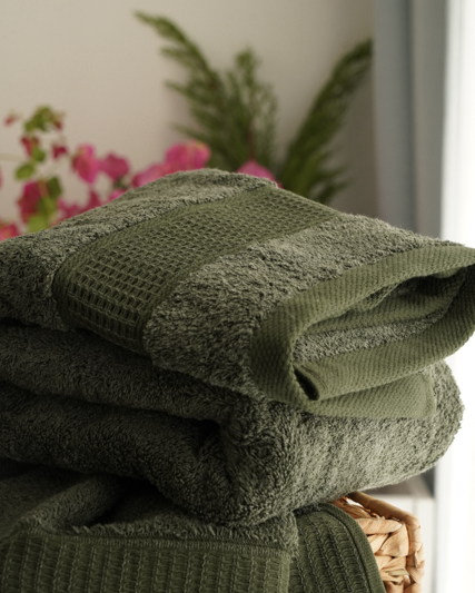 Stack of green towels with a blurred floral background