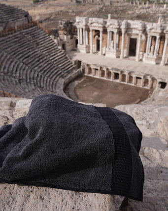Dark gray towel on a stone surface with an ancient amphitheater in the background