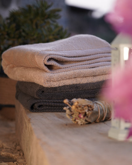 Honey Latte and Charcoal Embrace Plush Lite Aegean Cotton Bath Towels neatly folded, showcasing the soft texture and elegant colours of organic and luxury bath towels