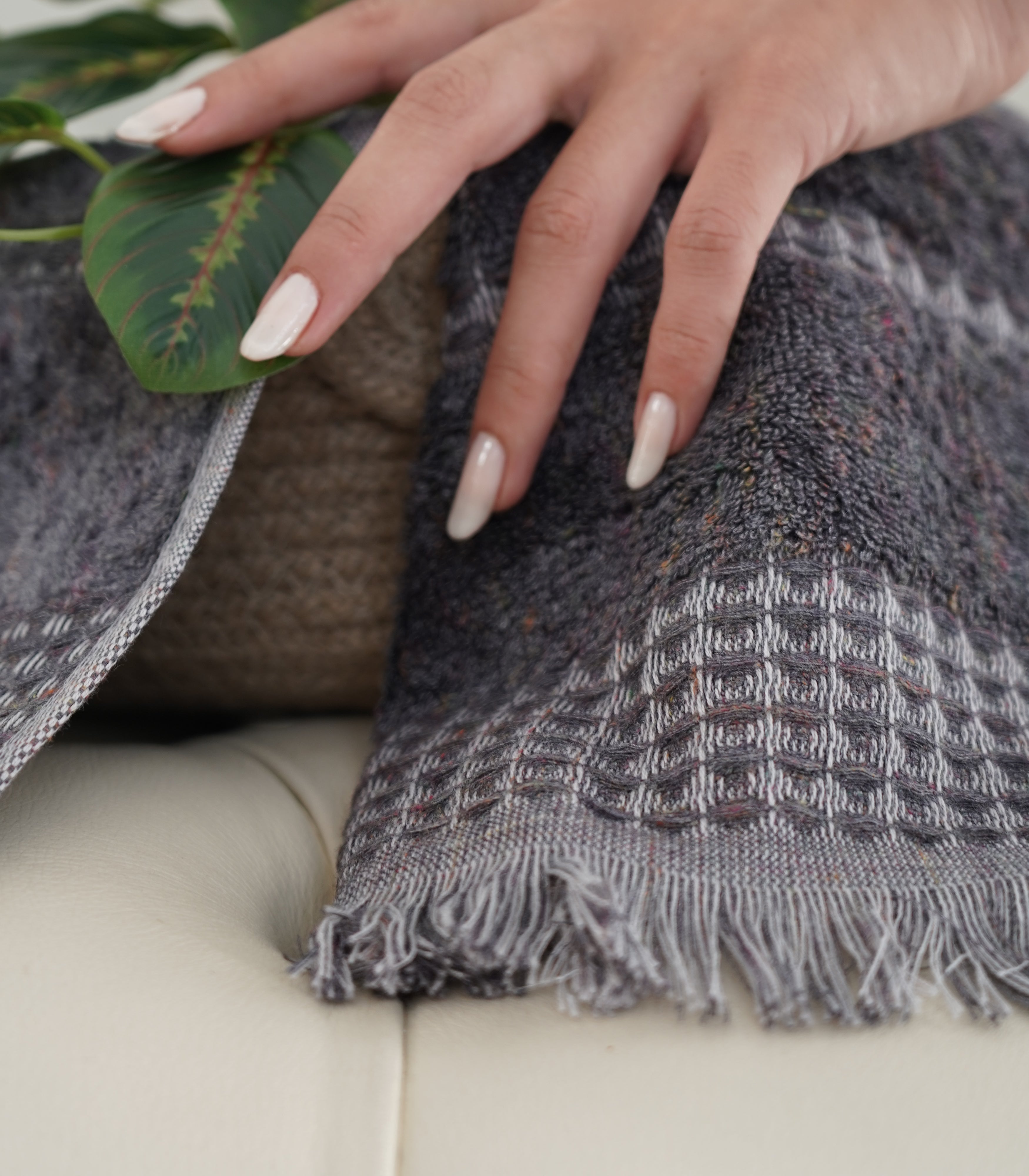 Zeus Organic Cotton Bath, Hand & Washcloth Set in Cozy Cobalt, with a woman’s hand gently holding the towels, accompanied by a plant, highlighting the soft texture, vibrant colour, and natural aesthetic