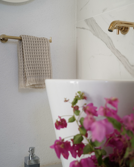 Minoa USA Canada Seren organic cotton waffle luxury bath towels displayed in a washroom with flowers, showing their plush texture, elegance, and sustainable luxury