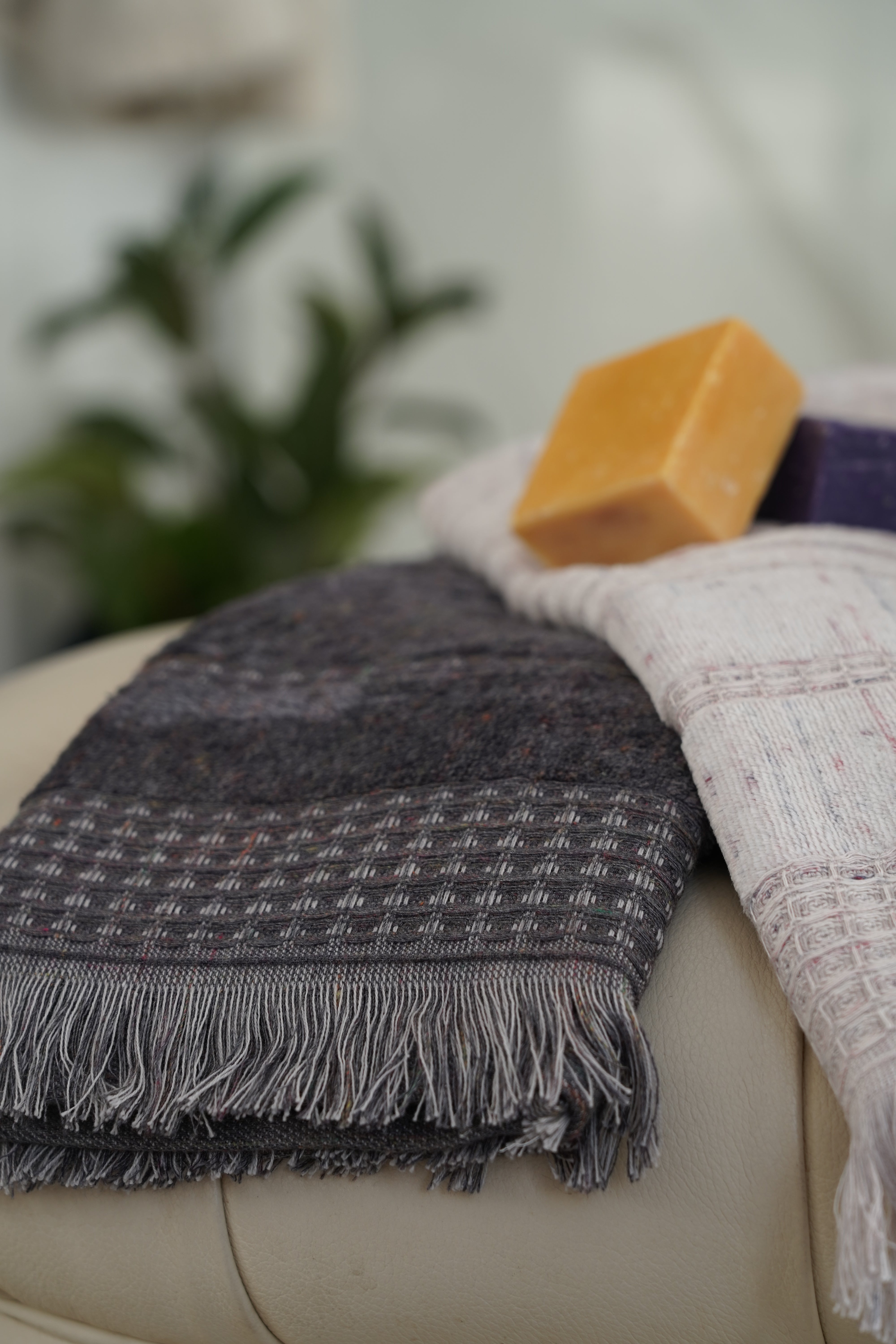 Close-up of the Zeus Organic Cotton Bath, Hand & Washcloth Set in Cozy Cobalt, with a woman’s hand gently holding or adjusting the towels, showcasing their soft texture and rich colour