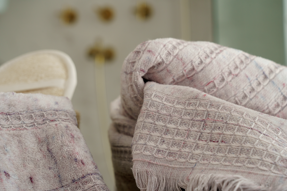 Minoa Maia organic cotton and viscose bath set with scrub in shower booth background showcasing sustainable luxury and the softness of organic bath towels in USA and Canada