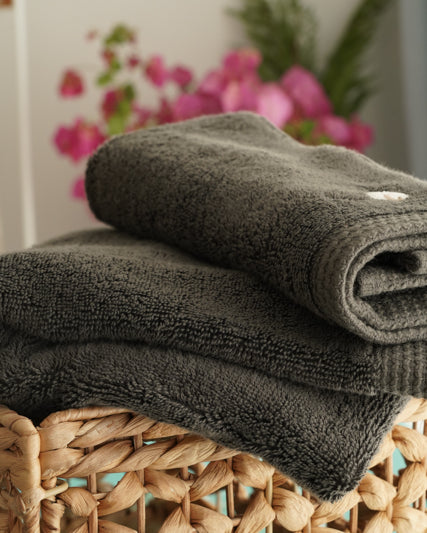 Minoa USA Canada Jasper organic Aegean cotton luxury bath towel set in a basket with a flowers background, highlighting soft plush texture and sustainable luxury