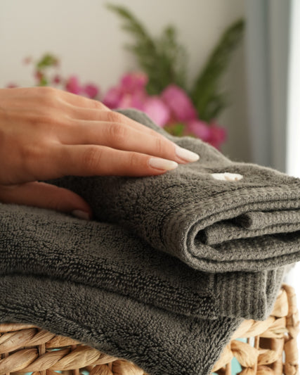 Minoa USA Canada Jasper organic Aegean cotton luxury bath towel set with a woman's hand touching it, highlighting soft plush texture, elegant design, and sustainable luxury