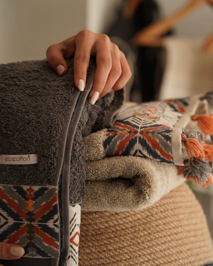 Woman touching Minoa USA Canada sustainable luxury bath towel from the Pamira Organic Aegean Cotton collection, highlighting soft texture, rich color, and premium organic fabric